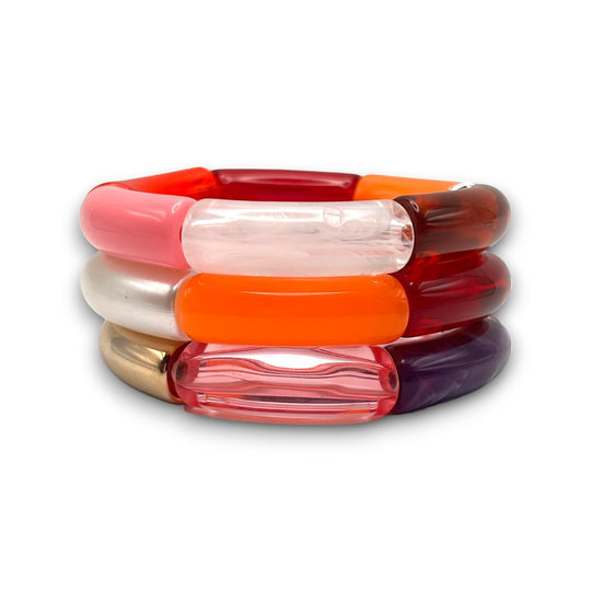 Three pink, orange, amber, and gold resin stretch bracelets stacked. 