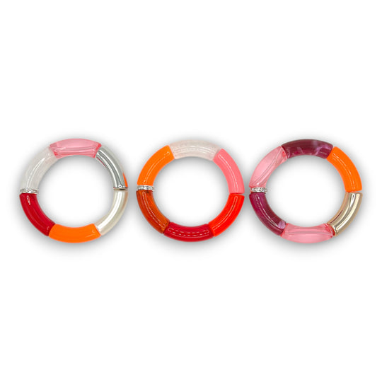 Three pink and orange resin stretch bracelets with a diamond rhinestone roundel. 
