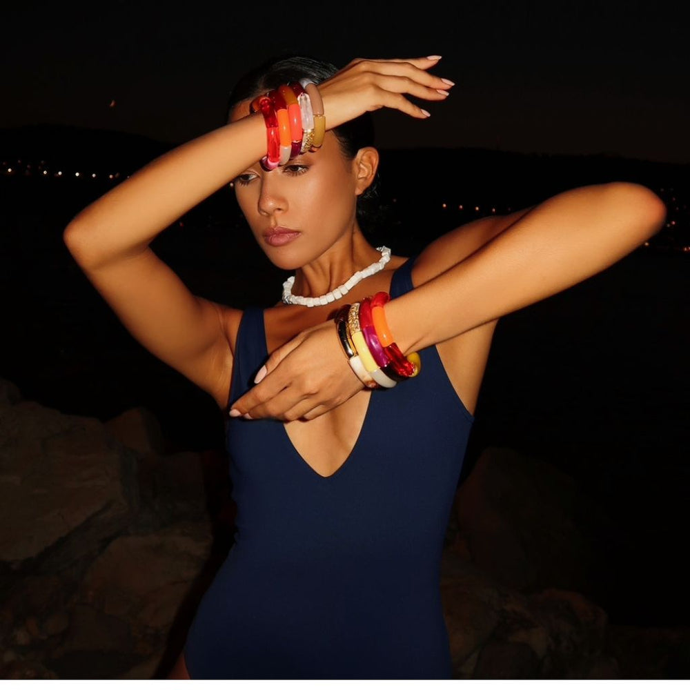 Girl wearing eight bright colored resin bangle bracelets with a white opal sterling silver necklace. 
