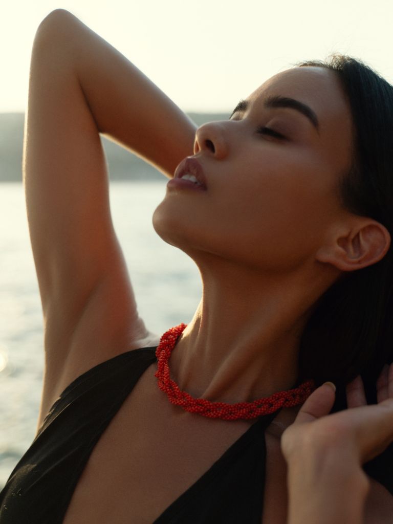 Girl wearing a red Mediterranean coral necklace delicately woven and then braided. 