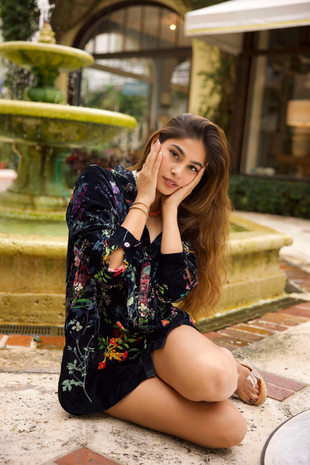 Girl sitting on the ground in Palm Beach wearing two 14K gold beaded bracelets. 
