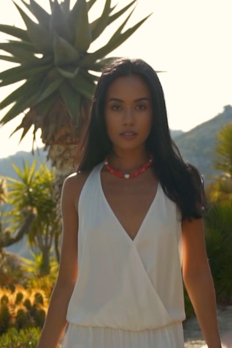 Girl in a garden wearing a red Sardinian coral necklace accented by three baroque pearls and a 14K gold filled clasp. 