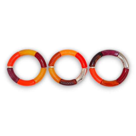 Three bright red, amber and gold beaded resin stretch bracelets with a diamond rhinestone roundel. 